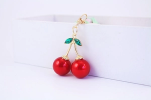Close-up of red crystal cherry keychain with golden stem and green rhinestone leaves