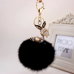 Detail of deer keychain with black fur pom-pom, cat eye stone, and sparkling rhinestones
