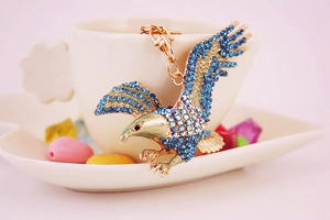 Detail of the golden eagle keychain with dark blue rhinestones on a ceramic cup