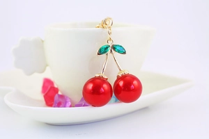 Detailed macro view of cherry charm with sparkling green rhinestones and red pearls