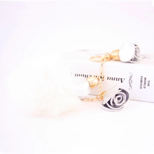 Fashion keychain with white faux fur pompom, silver leather roses, and gold metal chain