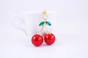 Detailed macro view of cherry earrings with red beads and green faceted glass leaves