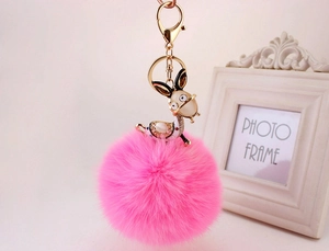 Detailed macro shot of a plush pink fur ball keychain with a gold rhinestone deer charm