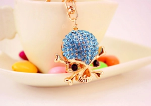 Dettaglio ravvicinato di un portachiavi a teschio dorato con strass blu chiaro brillanti