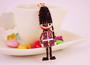 Detail view of a crystal-studded royal guard keychain beside a white coffee cup