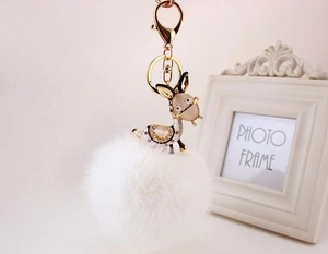 Detail of golden donkey keychain with white faux fur pompom and sparkling crystals