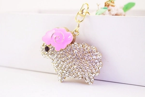 Detail of cute sheep keychain with sparkling rhinestones and pink enamel horn accents