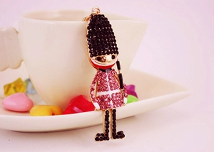 Detail of a sparkling crystal-encrusted royal guard keychain on a white coffee cup edge