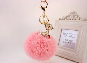 Detail of pink faux fur pompom keychain with crystal donkey charm and golden clasp