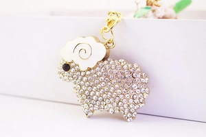 Macro shot of gold sheep keychain featuring pavé rhinestones and white enamel finish