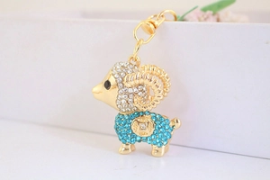Dettaglio portachiavi a forma di capra dorata con strass blu e bianchi e chiusura a moschettone