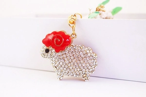 Detailed macro shot of a cute sheep keychain featuring sparkling white crystals and gold alloy