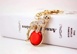 Detailed view of leopard keychain with white crystals and large red faceted gemstone