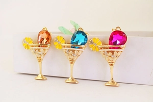 Dettaglio di ciondoli a forma di cocktail colorati con cristalli e limoni smaltati