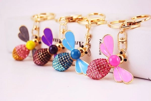 Detail of creative crystal bee keychains in pink, blue and purple with rhinestone accents