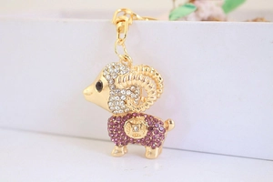 Dettaglio macro del portachiavi a forma di capra dorata con strass viola e bianchi e moschettone