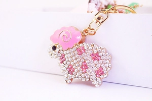 Close-up of pink and white rhinestone sheep keychain with gold lobster clasp and enamel details