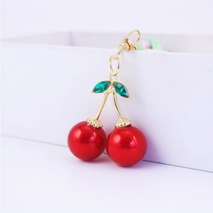 Sparkling red cherry keychain with green crystal leaves and golden metal ring
