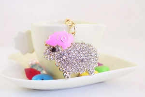 Detail of pink rhinestone sheep keychain hanging on a white coffee cup edge