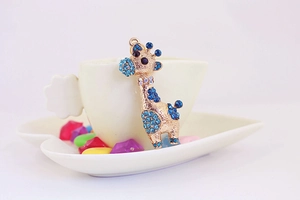 Détail d'un pendentif girafe doré orné de cristaux bleus brillants pour porte-clés