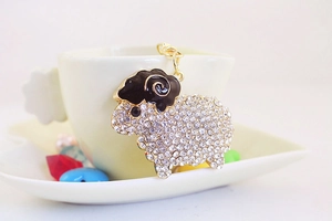 Close-up of sheep keychain with white rhinestones and black enamel on a ceramic cup
