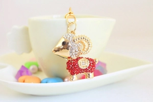 Detail of a golden sheep keychain with red and white rhinestones and a metal lobster clasp