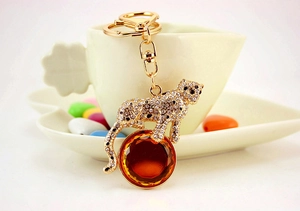 Detail of crystal leopard keychain with amber gemstone on a white ceramic tray