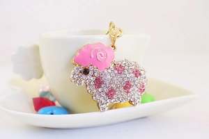 Pink rhinestone sheep keychain hanging on a white coffee cup with decorative beads
