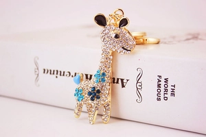 Detail of a golden giraffe keychain featuring sparkling rhinestones and blue floral accents