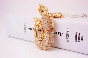 Close-up of golden lobster keychain with white rhinestones on a white book