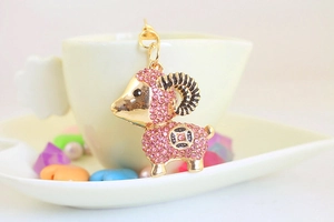 Close-up of pink crystal sheep earring hanging on a ceramic cup with decorative beads