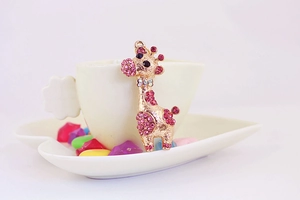 Gros plan d'un porte-clés girafe doré avec strass roses et détail de nœud coloré