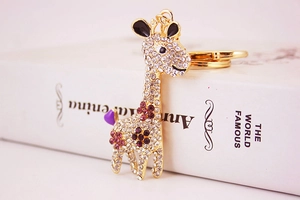 Detail of crystal studded giraffe keychain with gold finish and purple rhinestone spots