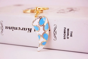 Close-up of golden horn pendant keychain with blue enamel and white rhinestones