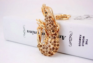 Macro shot of gold lobster keychain with brown rhinestones resting on white books