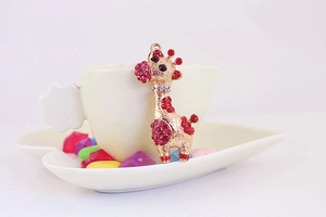 Détail du porte-clés girafe avec cristaux rouges et roses sur une tasse blanche