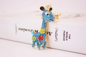 Detail of cute giraffe keychain with blue crystals and floral pattern on gold metal
