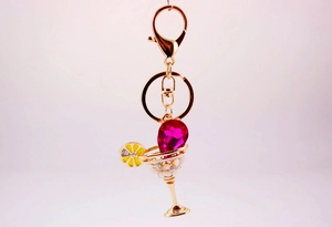 Detail of cocktail glass keychain with rose red gemstone and lemon slice charm
