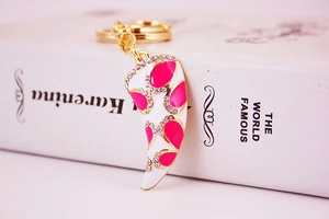 Close-up of pink enamel horn keychain with sparkling rhinestones on a book
