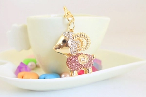 Detailed view of a golden sheep keychain with pink rhinestones and lobster clasp hooks