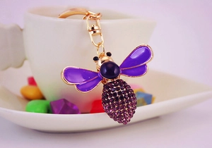Close-up of purple crystal bee keychain with gold plating and rhinestones detailing