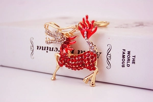 Macro view of gold kirin keychain featuring red rhinestones and enamel details on white book