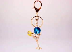 Detail view of crystal cocktail glass keychain with blue teardrop gemstone and gold alloy finish