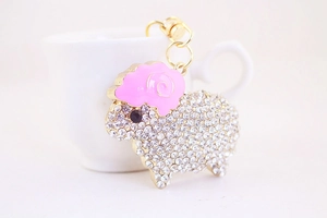 Macro detail of cute sheep keychain with sparkling white crystals and pink enamel accents