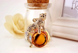 Close-up of golden leopard keychain with white rhinestones holding a large amber crystal