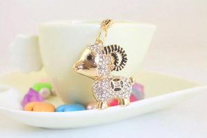 Macro detail of cute golden goat keychain with sparkling rhinestones and black enamel horns