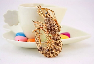 Macro detail of gold lobster keychain with sparkling brown rhinestones on a white cup