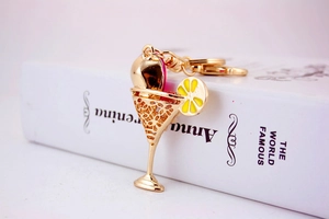 Detailed view of golden cocktail glass keychain with pink inlay and lemon slice accent