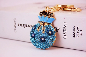 Detail of blue rhinestone money bag keychain with polished gold hardware on a book