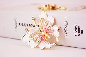 Détail d'un porte-clés papillon doré avec des ailes en émail blanc et des strass brillants